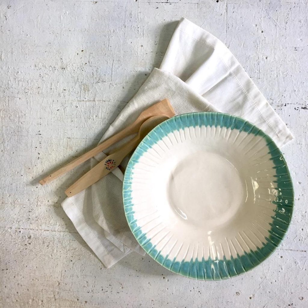 Assiette blanche au bord turquoise et cuillères en bois
