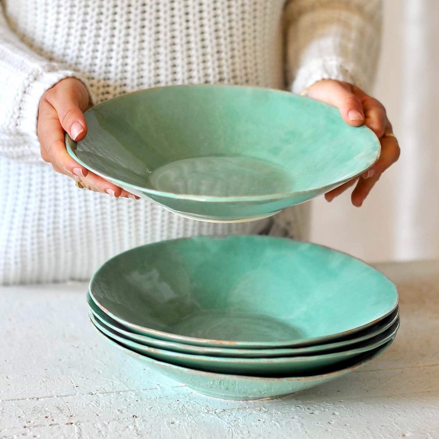 Assiettes creuses céladon, l’une tenue au-dessus de la pile