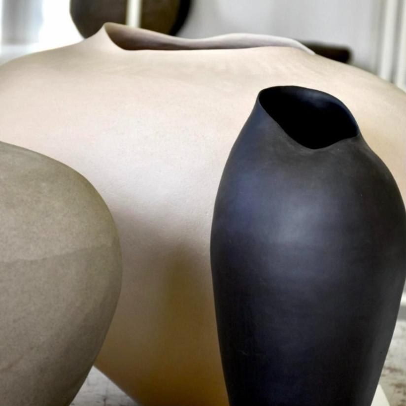 Vase noir devant une grande jarre beige
