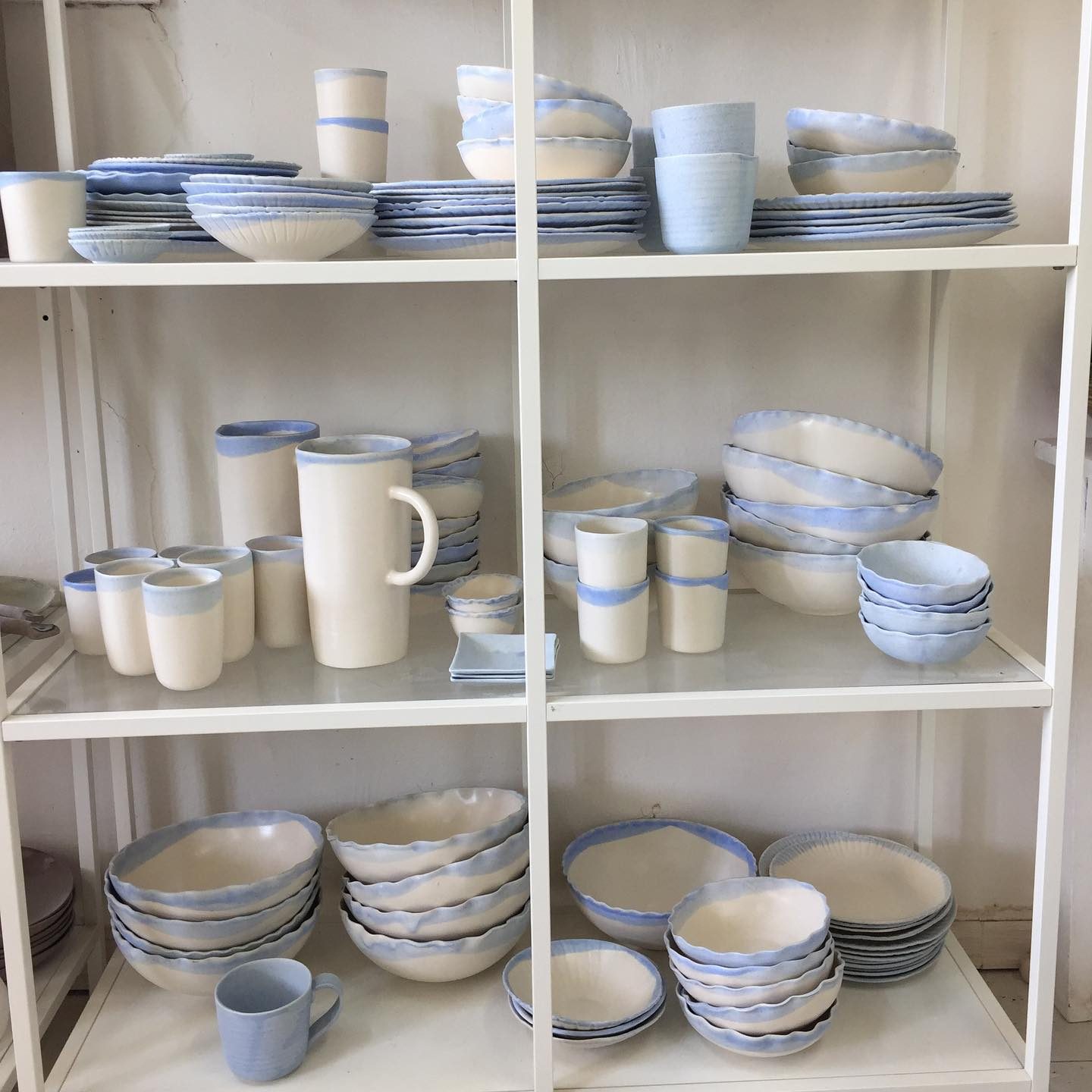 Étagères de l’atelier garnies de vaisselle bleue et blanche